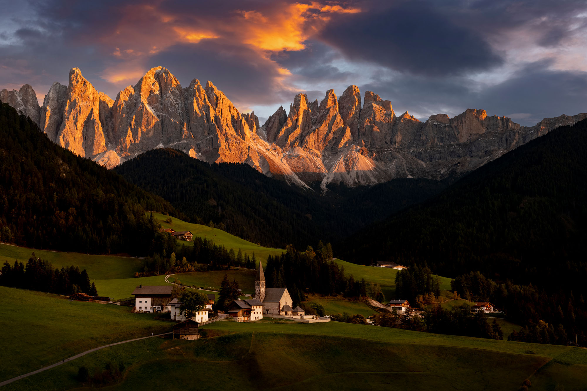 Santa Maddalena au sunset avec des nuages oranges dans le ciel.