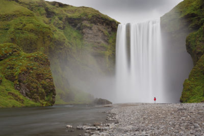 Personnage devant Skogafoss en Islande.