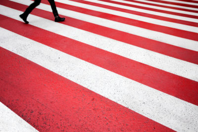 Personnage sur un passage piéton rouge et blanc.
