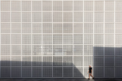 Personnage marchant devant d'immenses grilles métalliques au musée du Louvre d'Abu Dhabi.