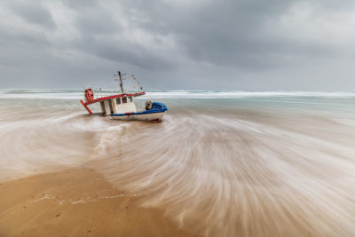 Bateau échoué sur une plage de sable.