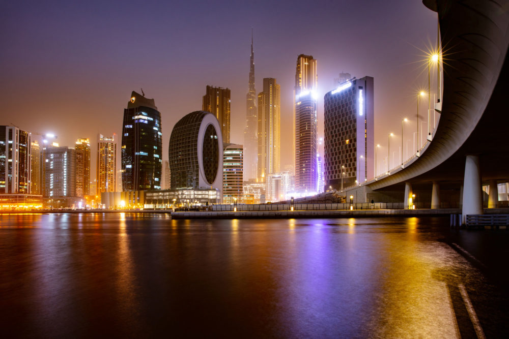 Les buildings de Dubaï de nuit avec un pont au premier plan.