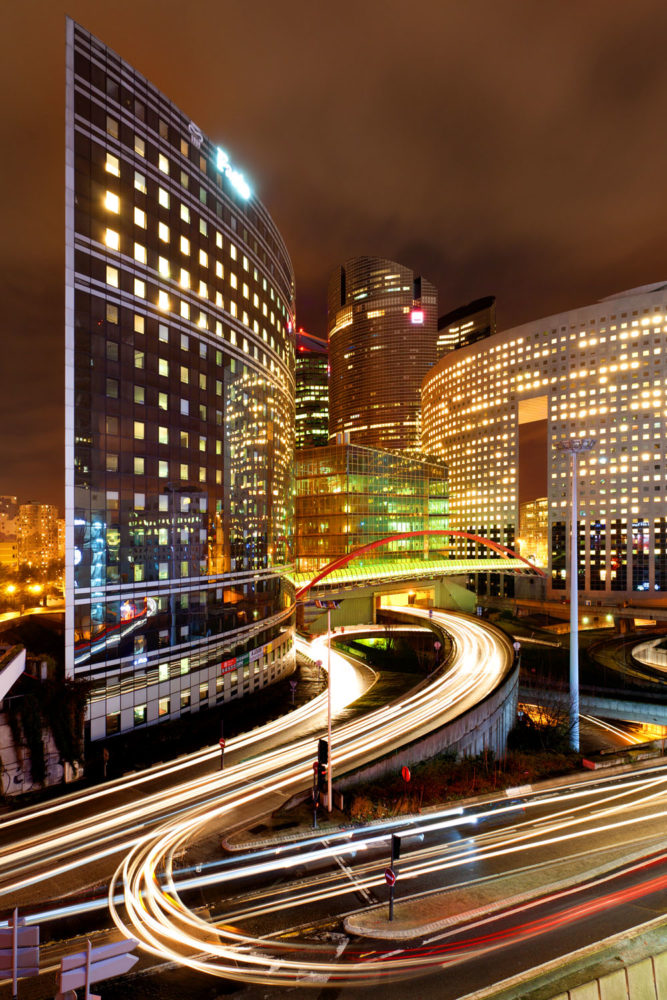 Le quartier de La Défense à Paris pendant la nuit avec des filés de voitures.
