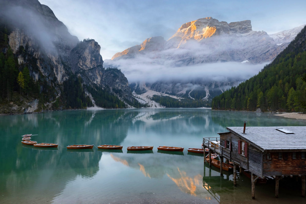 Le lago di braies le matin avec les barques, le soleil qui se lève, des reflets et de la brume.