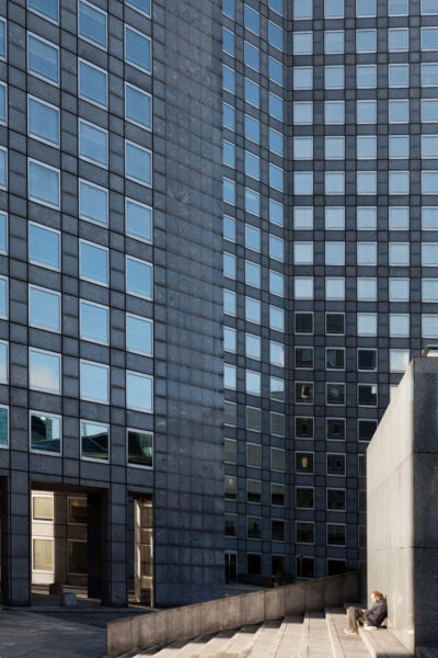 Personnage au pied des tours de la Défense à Paris.