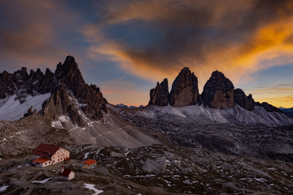 Les tre cime di lavaredo avec le refuge locatelli au sunset. Nuages oranges dans le ciel.