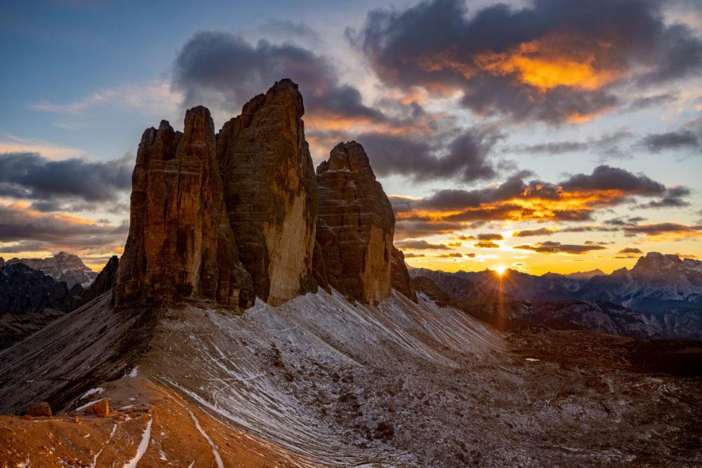 Les tre cime di lavaredo au sunset avec des nuages oranges dans le ciel.